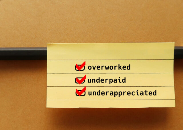 Office envelope with text note written OVERWORKED UNDERPAID and UNDERAPPRECIATED - Feeling undervalued at work or feel like your efforts go unnoticed.